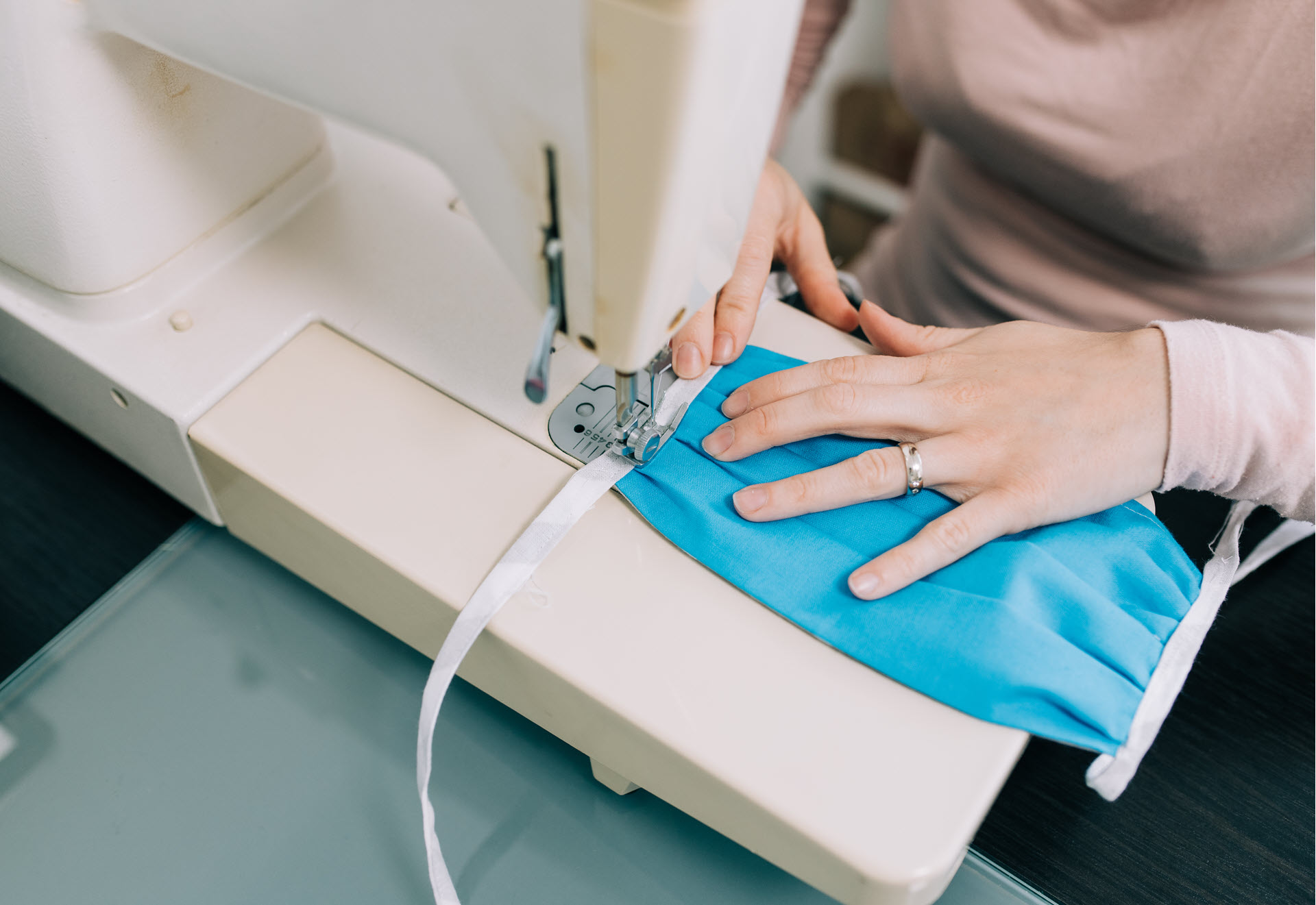 Women sewing a mask on a sewing machine to earn extra money